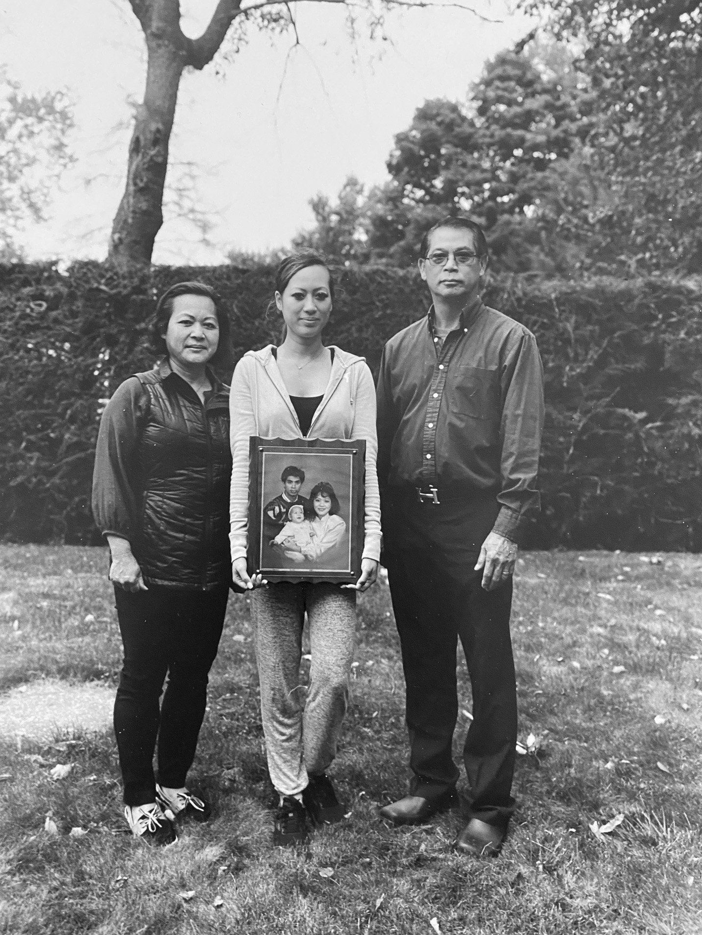 Three people standing together while holding a portrait of three people